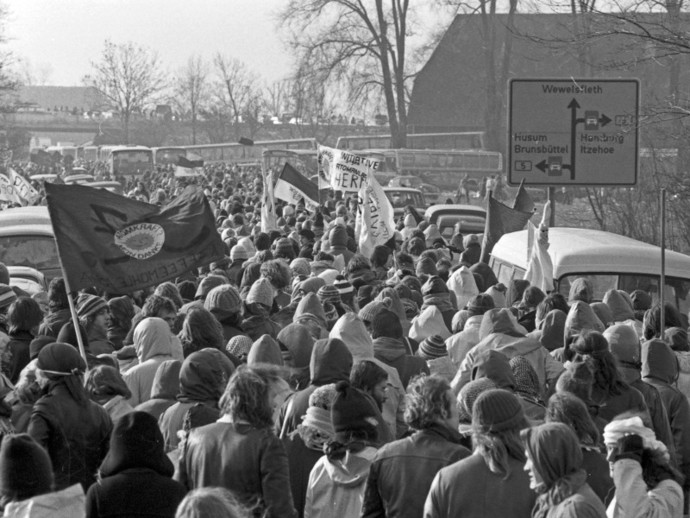 Sehr viele Demonstranten gehen mit Protestbannern in Richtung des AKW Brokdorf, um gegen den Bau zu demonstrieren (© picture alliance / United Archives/ Roba-Archiv) Sehr viele Demonstranten gehen mit Protestbannern in Richtung des AKW Brokdorf, um gegen den Bau zu demonstrieren