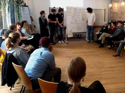Präsentation an einer Stellwand vor Zuhörern im Stuhlkreis (© BASE) Präsentation an einer Stellwand vor Zuhörern im Stuhlkreis